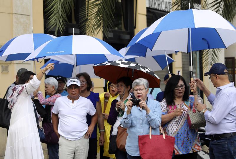 En la imatge, un grup de turistes es protegeixen de la pluja en el centre de València.