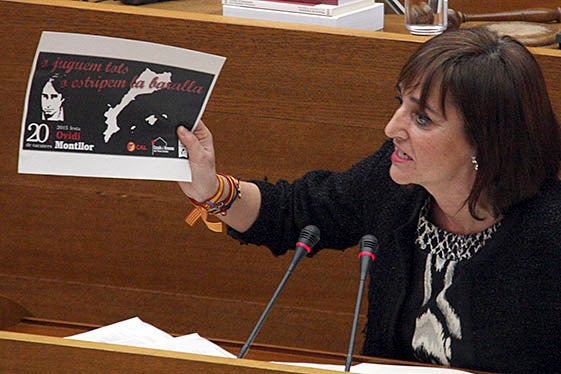 La diputada del PP valencià, Mayte Parra, mostra a la cambra un cartell commemoratiu dels 20 anys de la mort de l'Ovidi Montllor.