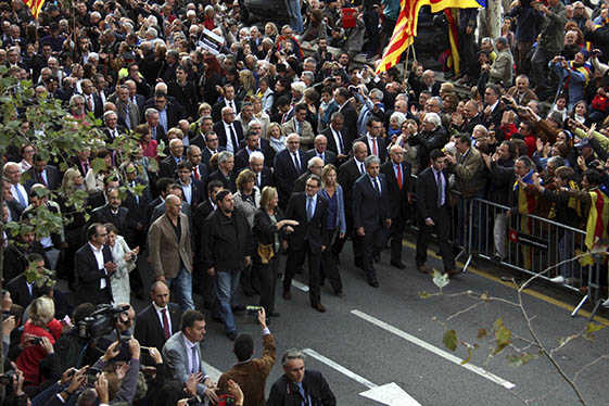 Mas acompanyat del Govern, diputats de Junts pel Sí i els alcaldes avança cap al TSJC envoltat de persones que l'animen.