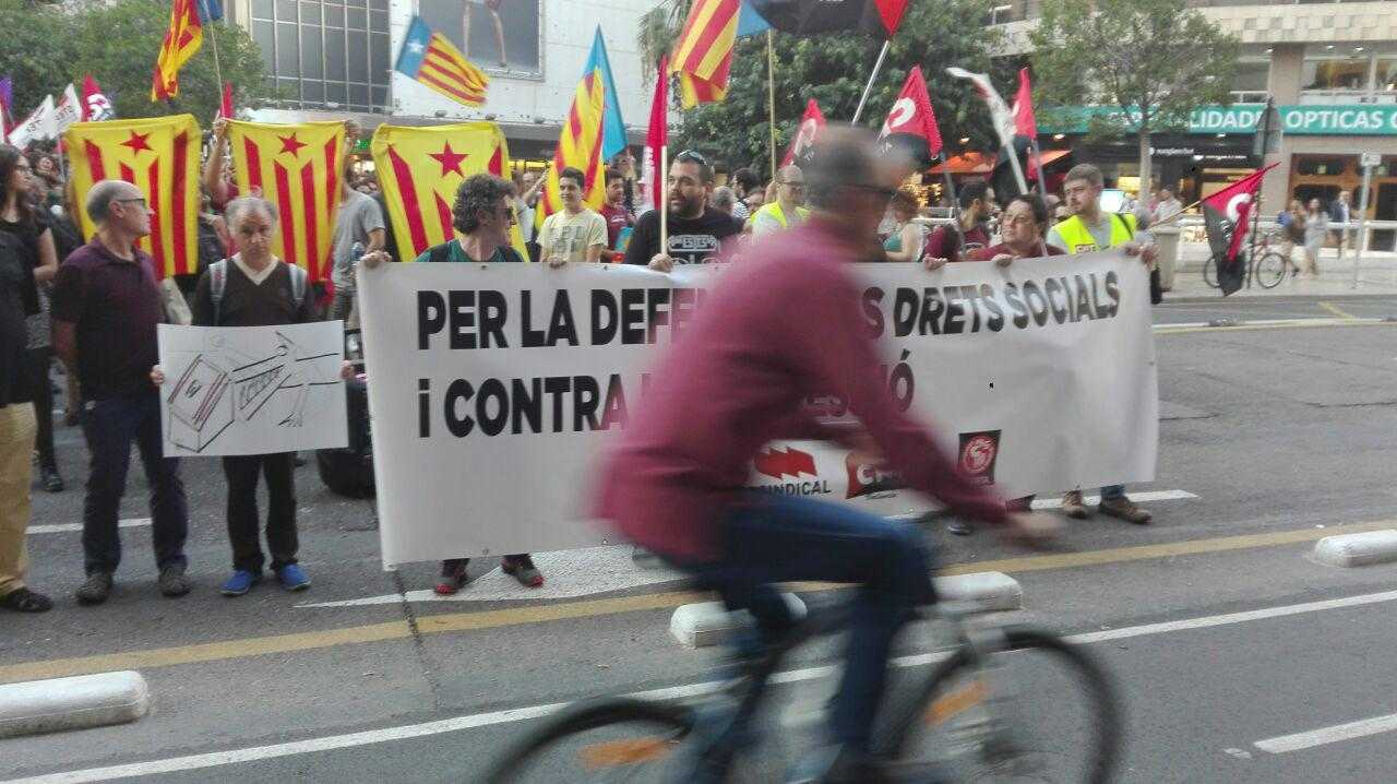 Un ciclista passa davant de la pancarta principal de la concentració de suport al poble català celebrada a València.