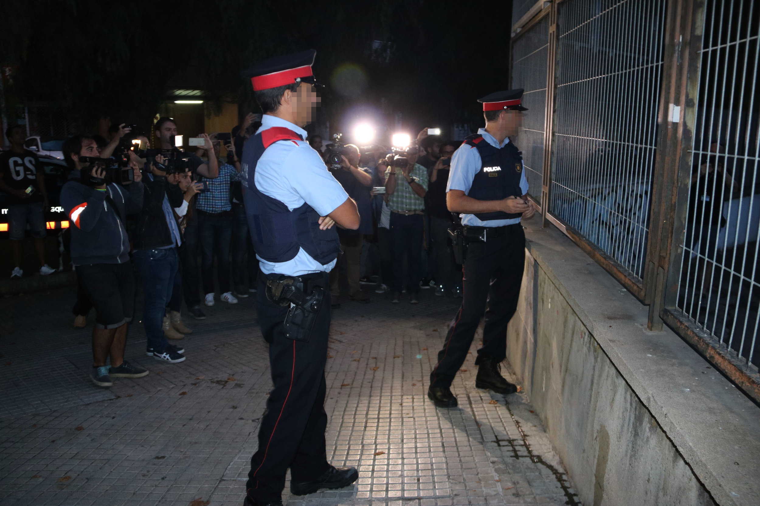 Dos agents dels Mossos que miren el recinte de l'institut Antoni Martí i Franquès de Tarragona, davant desenes de mitjans.