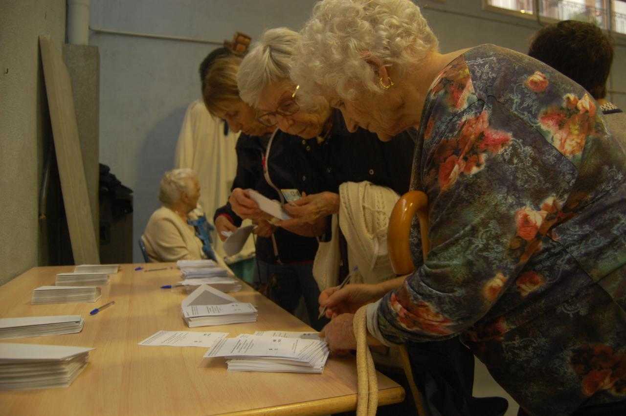 Quatre dones agafen les pareretes de votació al col·legi electoral Reina Violant de Barcelona.