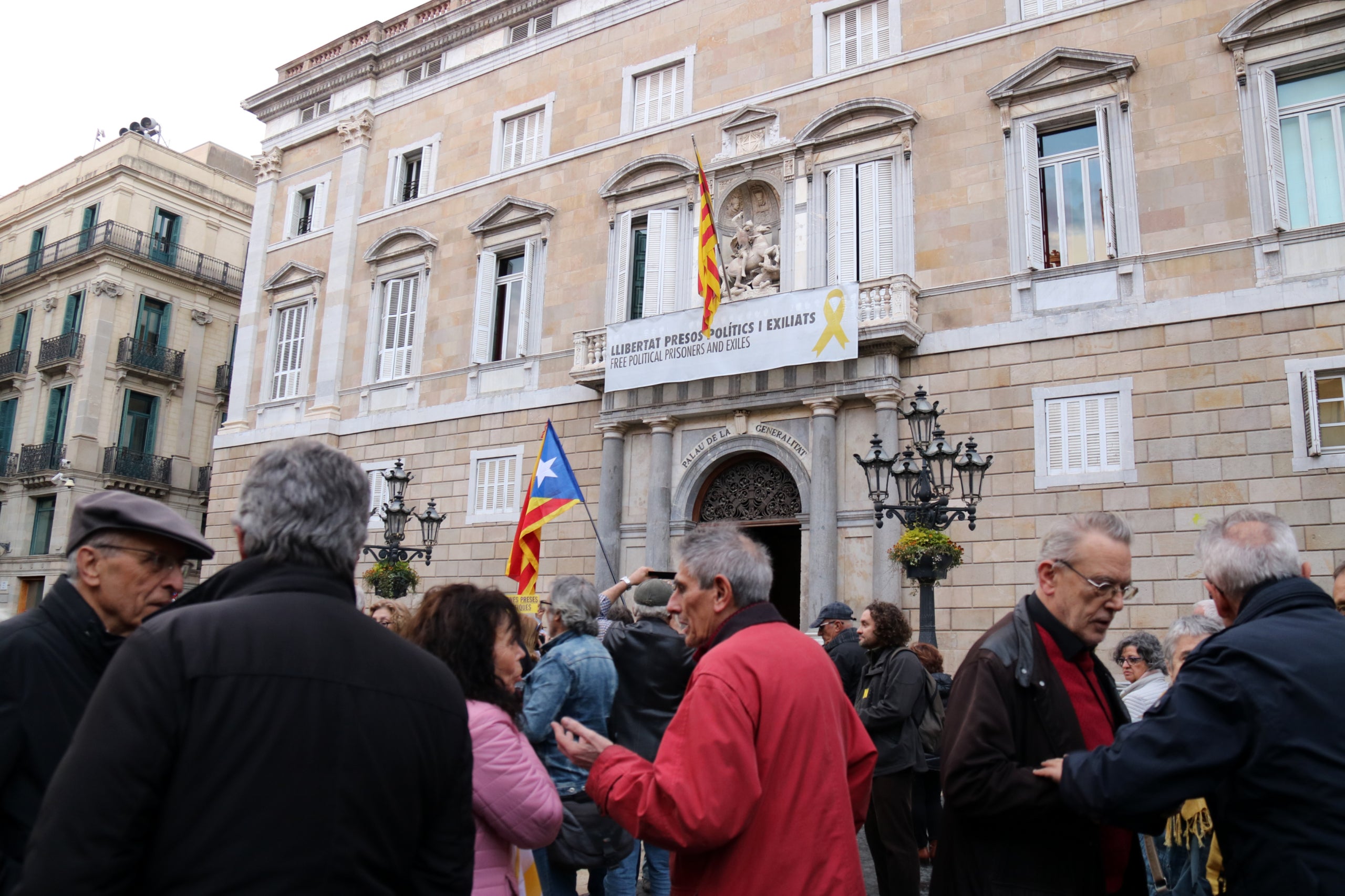 Desenes de persones davant el balcó de la Generalitat on hi ha la pancarta que demana 'llibertat presos polítics'. / CAROLA LÓPEZ / ACN
