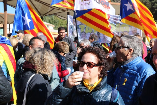 Primer pla d'una manifestant prenent un vermut amb la frontera al fons aquest dissabte. / GERARD VILÀ, ACN