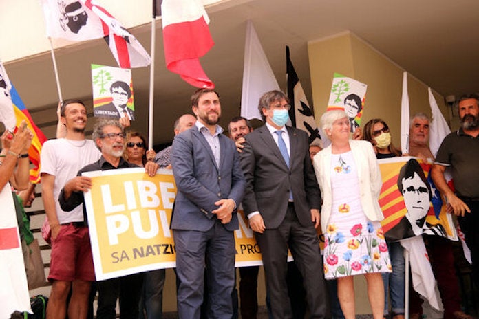 Puigdemont, Comín i Ponsatí a la sortida del tribunal de Sàsser i davant una pancarta de suport | Natàlia Segura | ACN