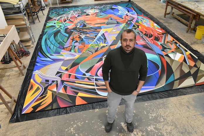 L'artista Javier Parra davant del mural de Josep Renau que ha dut a terme | NLV