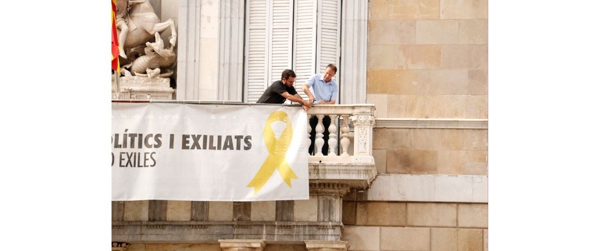 Dos treballadors comencen a treure la pancarta dels presos del Palau de la Generalitat | Blanca Blay | ACN