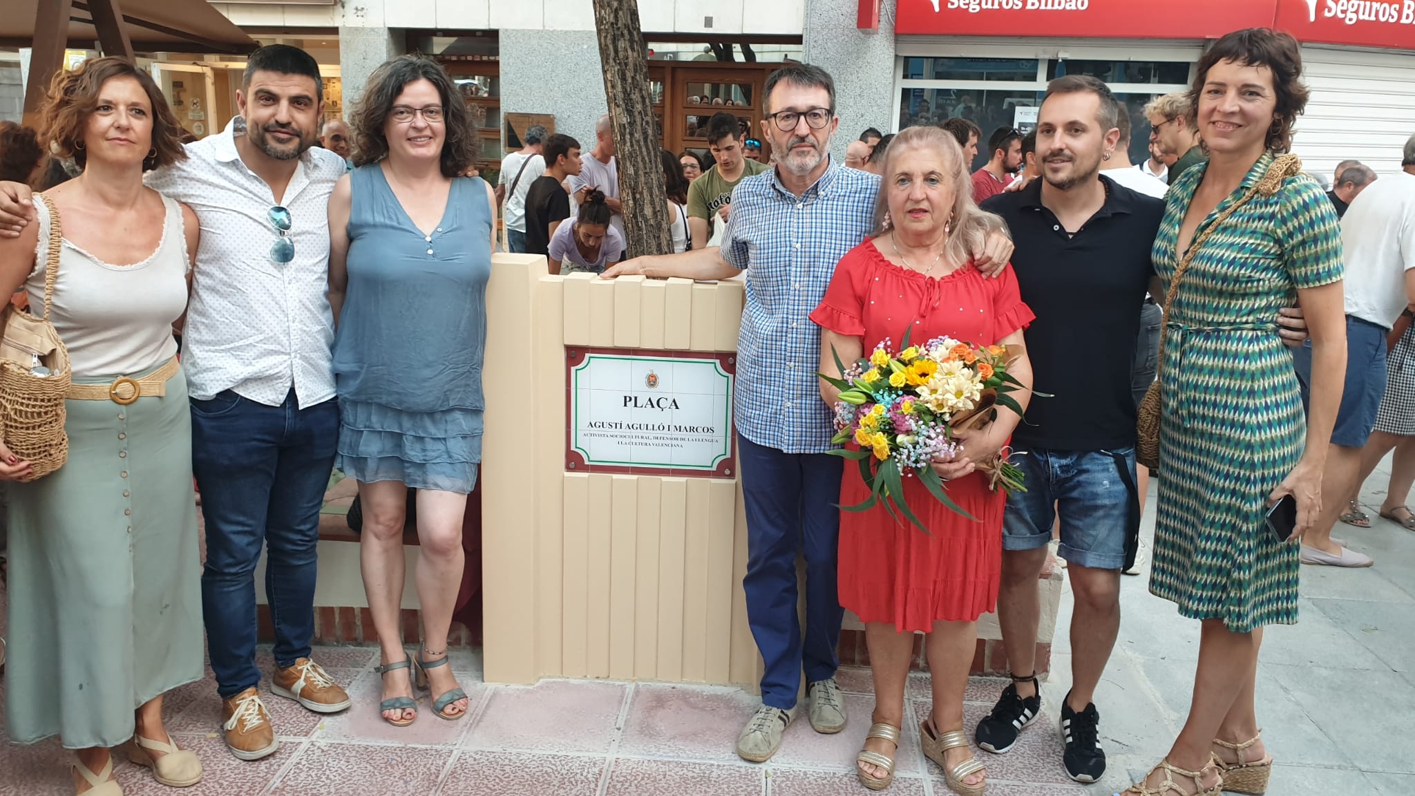 Representants d'Acció Cultural amb Maribel Molina, vídua d'Agustí Agullo, al costat de la placa dedicada a l'activista il·licità