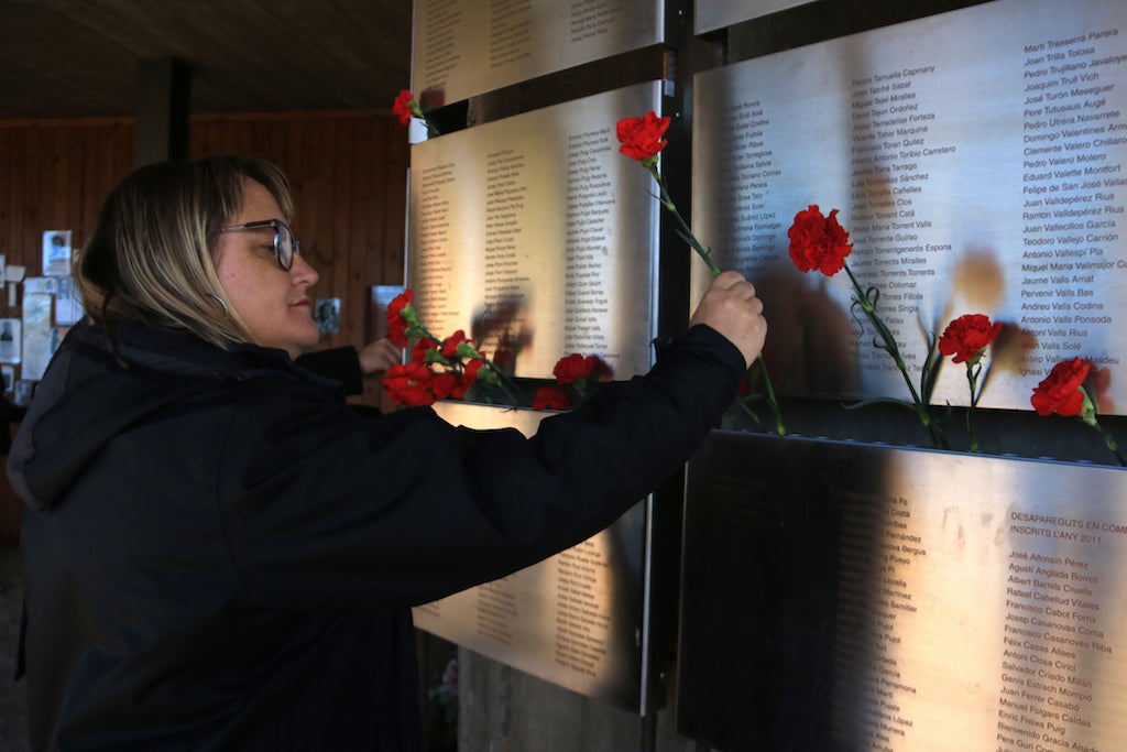 Una dona col·loca clavells al Memorial de les Camposines de la Fatarella | Ariadna Escoda | ACN