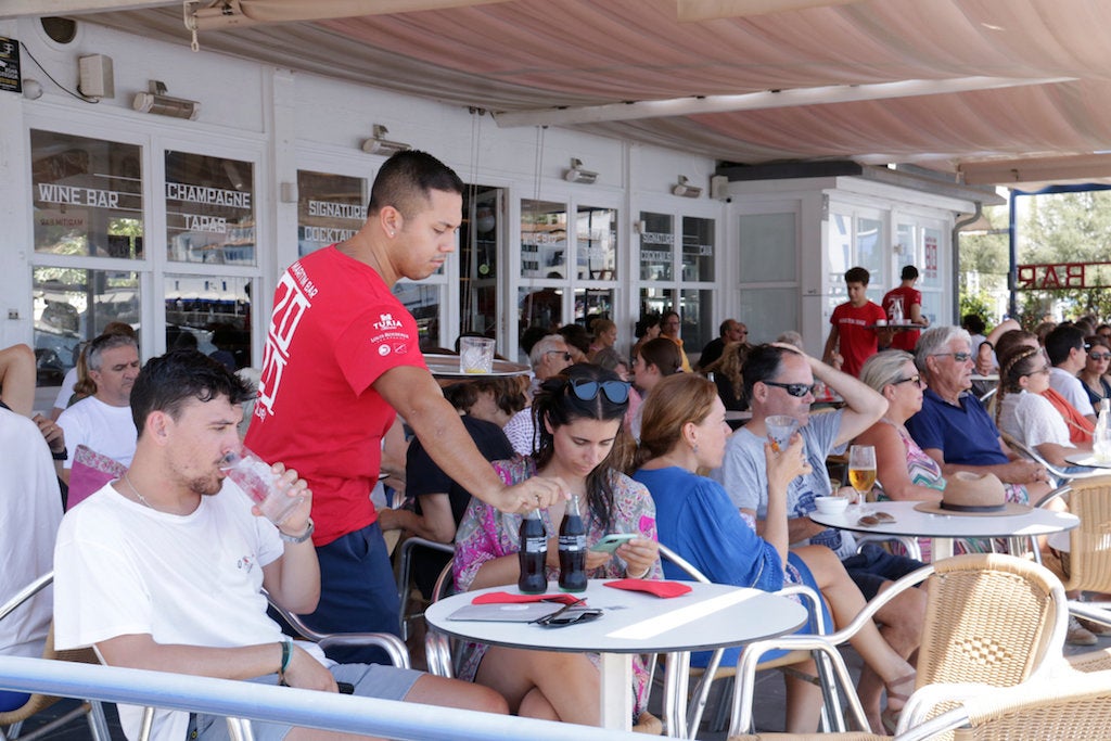 Un cambrer servint una taula en un bar de primera línia de platja | Marina López | ACN