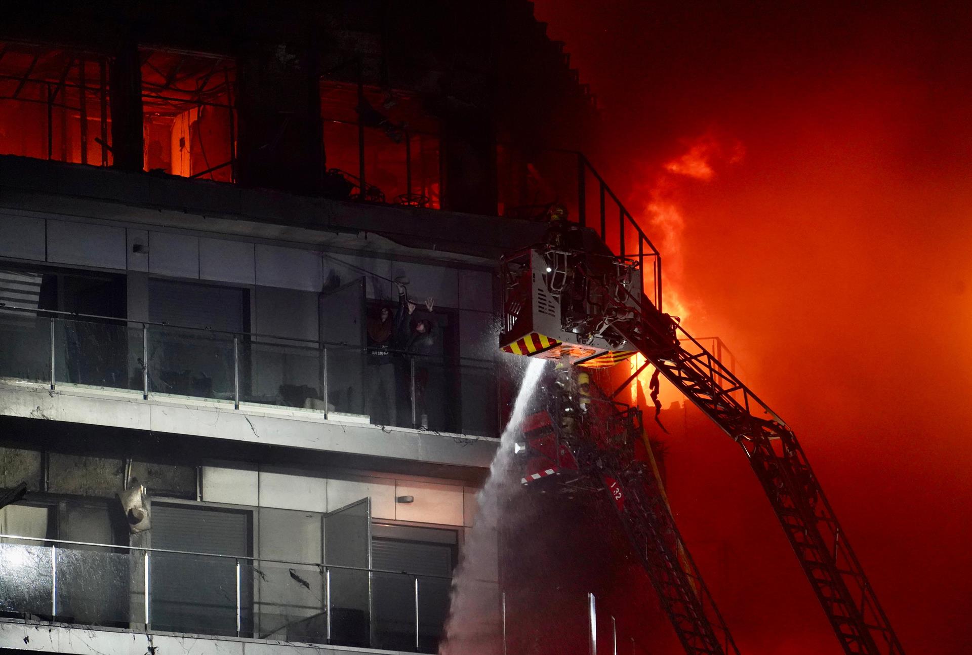 Un bomber treballa per a rescatar dues persones atrapades a l'edifici incendiat a Campanar | Eduardo Manzana | EP