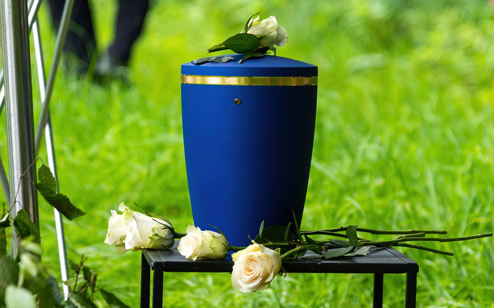 one blue urn and white roses prepared for funeral at a green field