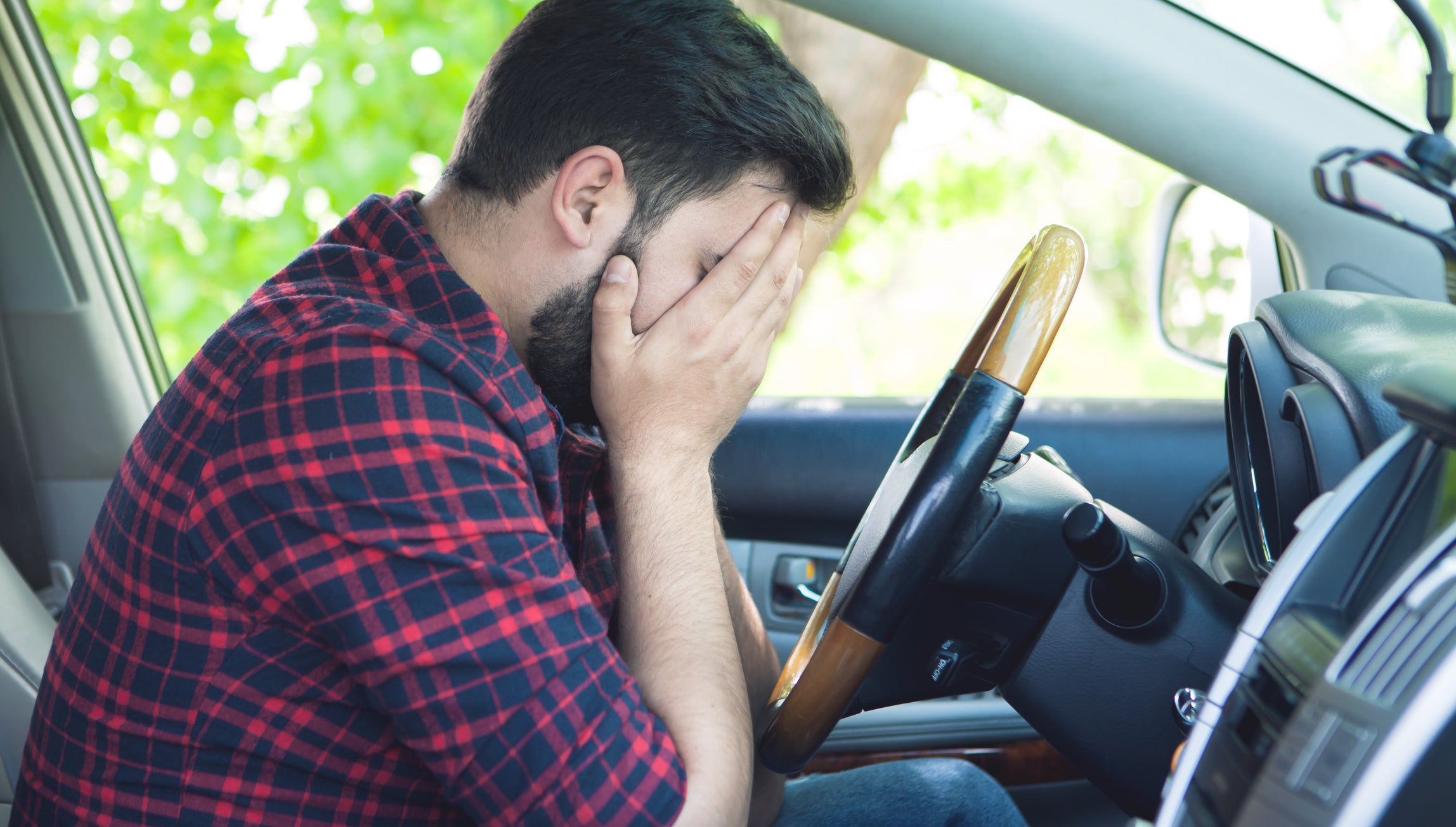 tired, angry, young driver covers his face by hands