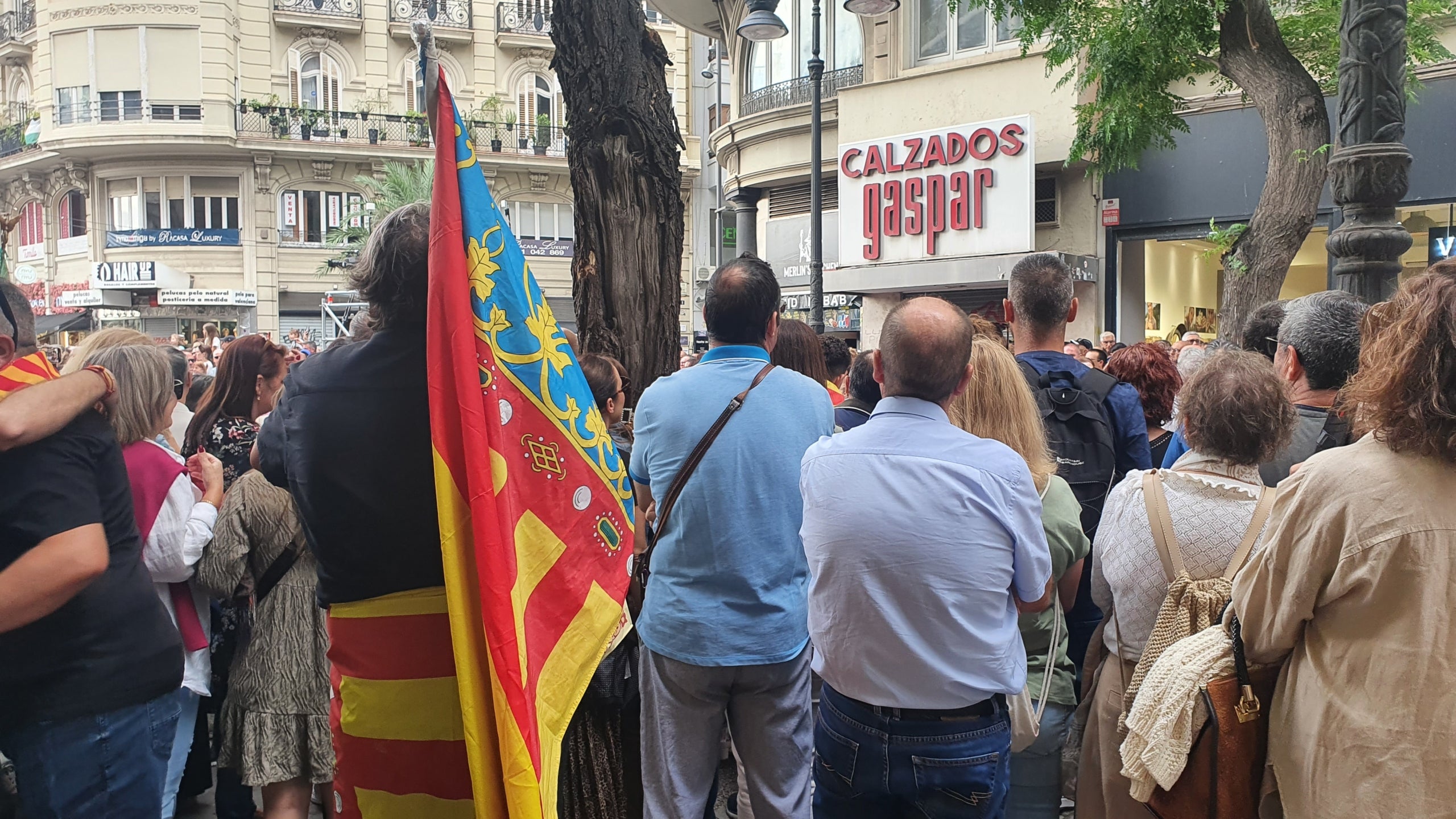 Un home amb dues senyeres coronades xiula els representants públics de Compromís | Josan Piqueres