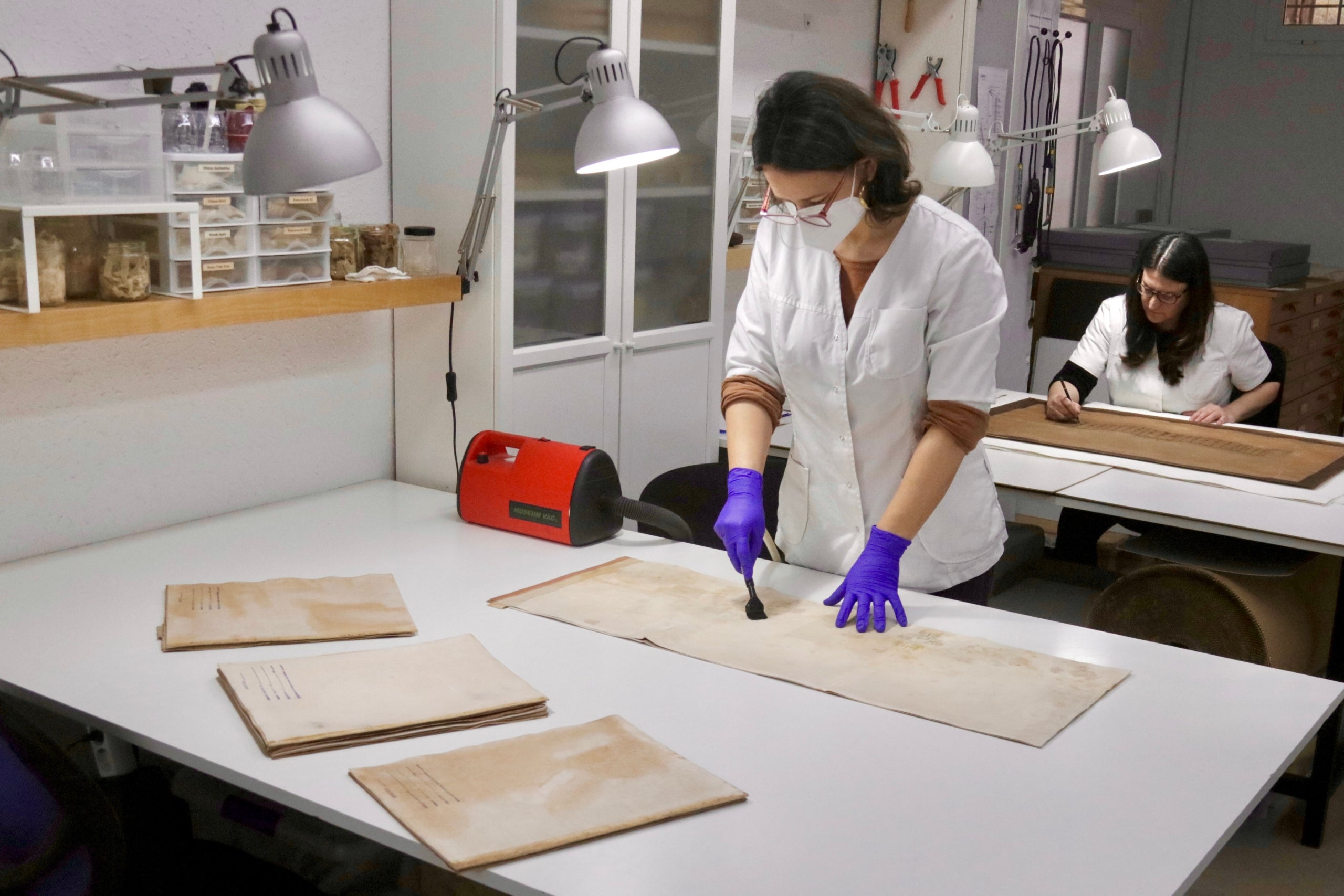 La restauradora Berta Blasi al seu taller, treballant amb documentació del Sindicat Arrosser d'Alfafar afectada per la dana | Jordi Pujolar | ACN