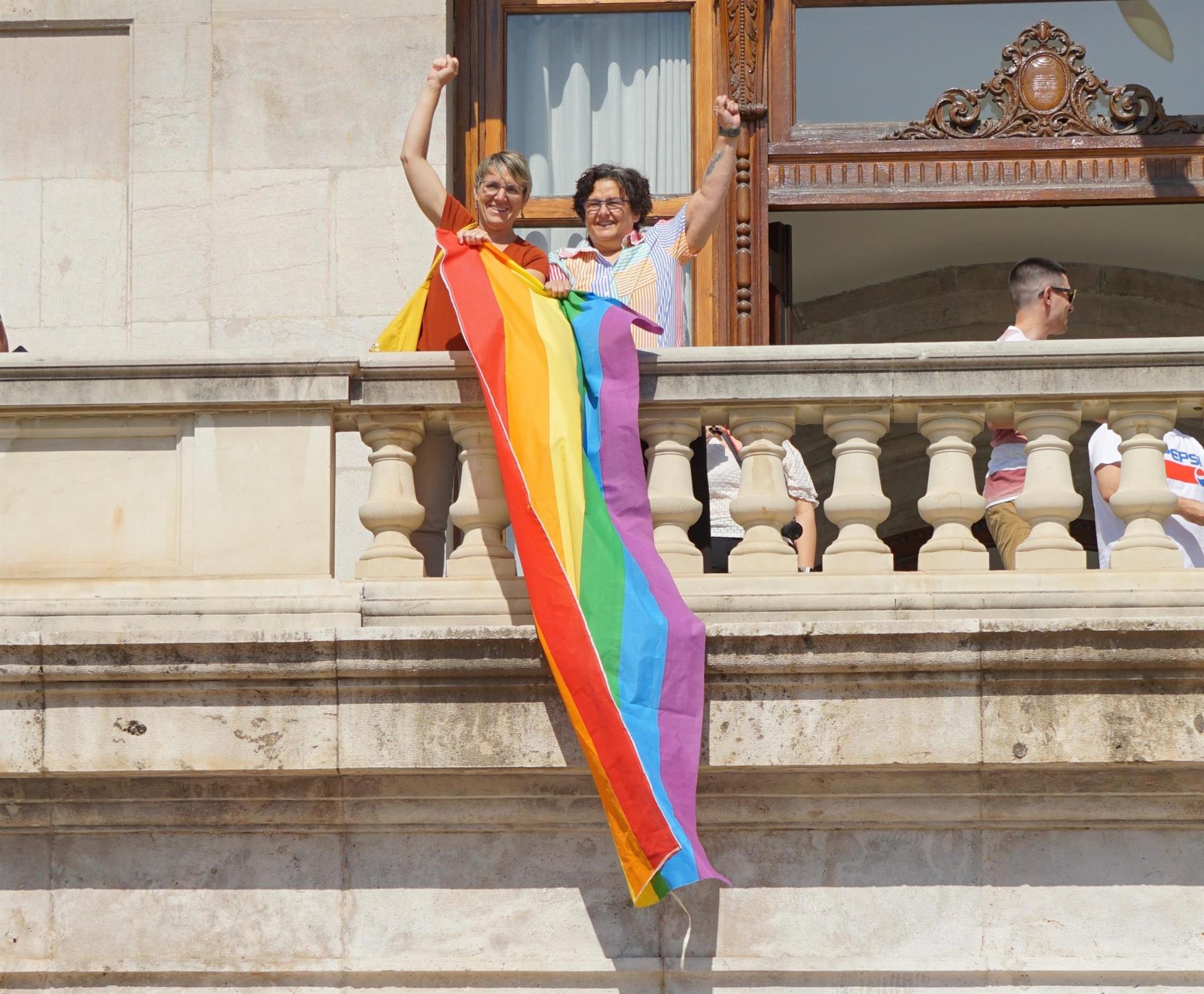 La portaveu de Compromís a l'Ajuntament de València, Papi Robles, i l'edil de la formació, Lluïsa Notario, amb la bandera LGTBI+ al balcó del consistori | EP