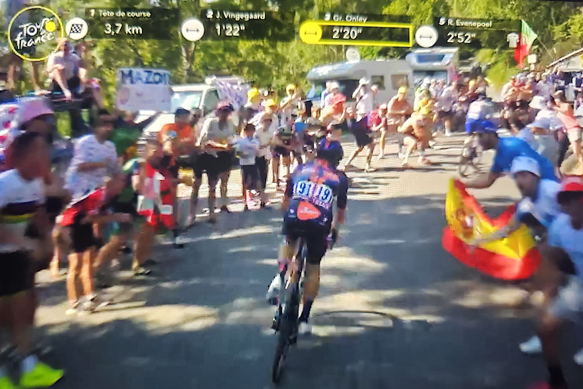 Un aficionat al ciclisme mostra un cartell de 'Mazón, dimissió' en una etapa del Tour de França 2025