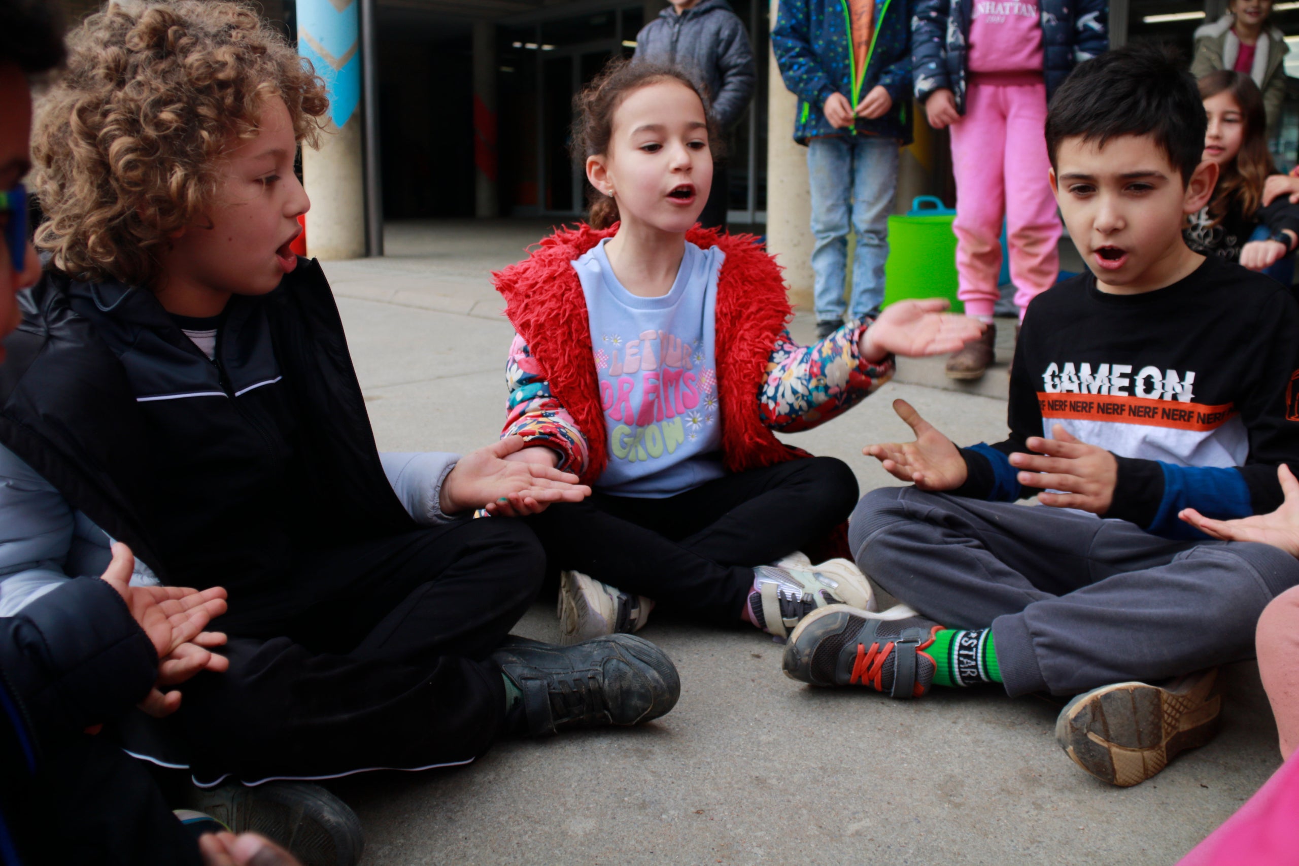Xiquets i xiquetes jugant i cantant en català al pati d’una escola. Lourdes Casademont - ACN.
